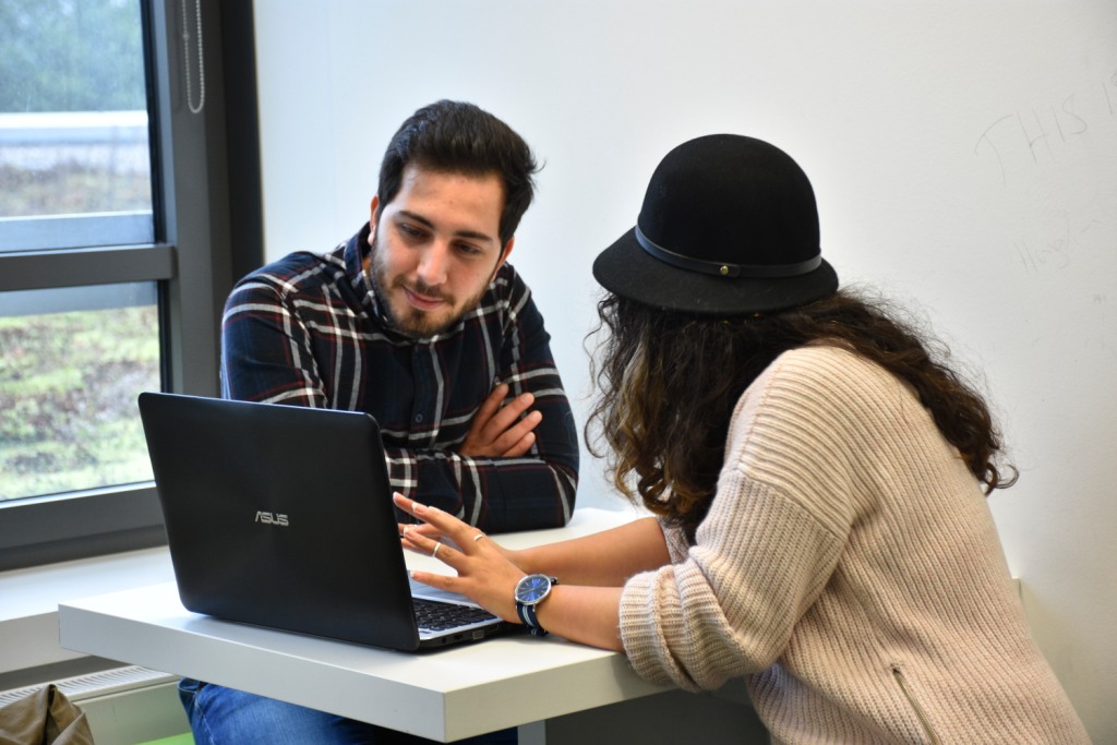 Zwei Personen sitzen gemeinsam an einem Laptop und arbeiten