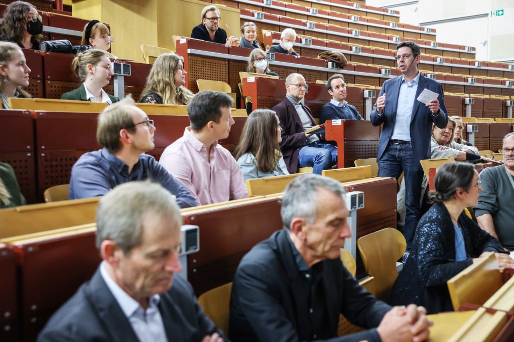 Dr. André Fleer steht im Hörsaal und spricht ins Mikrofon.