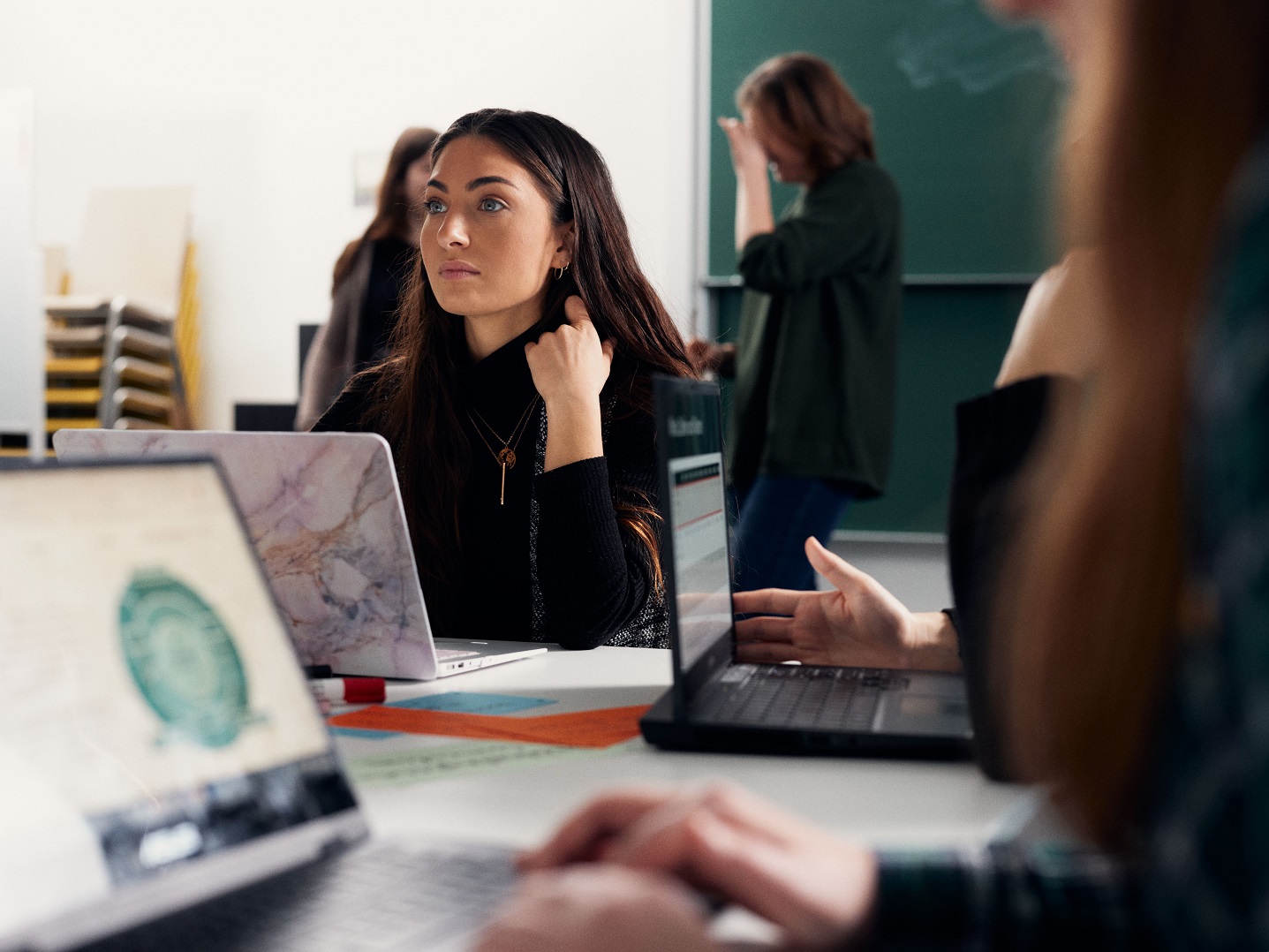 Personen sitzen mit Laptops an einem Tisch