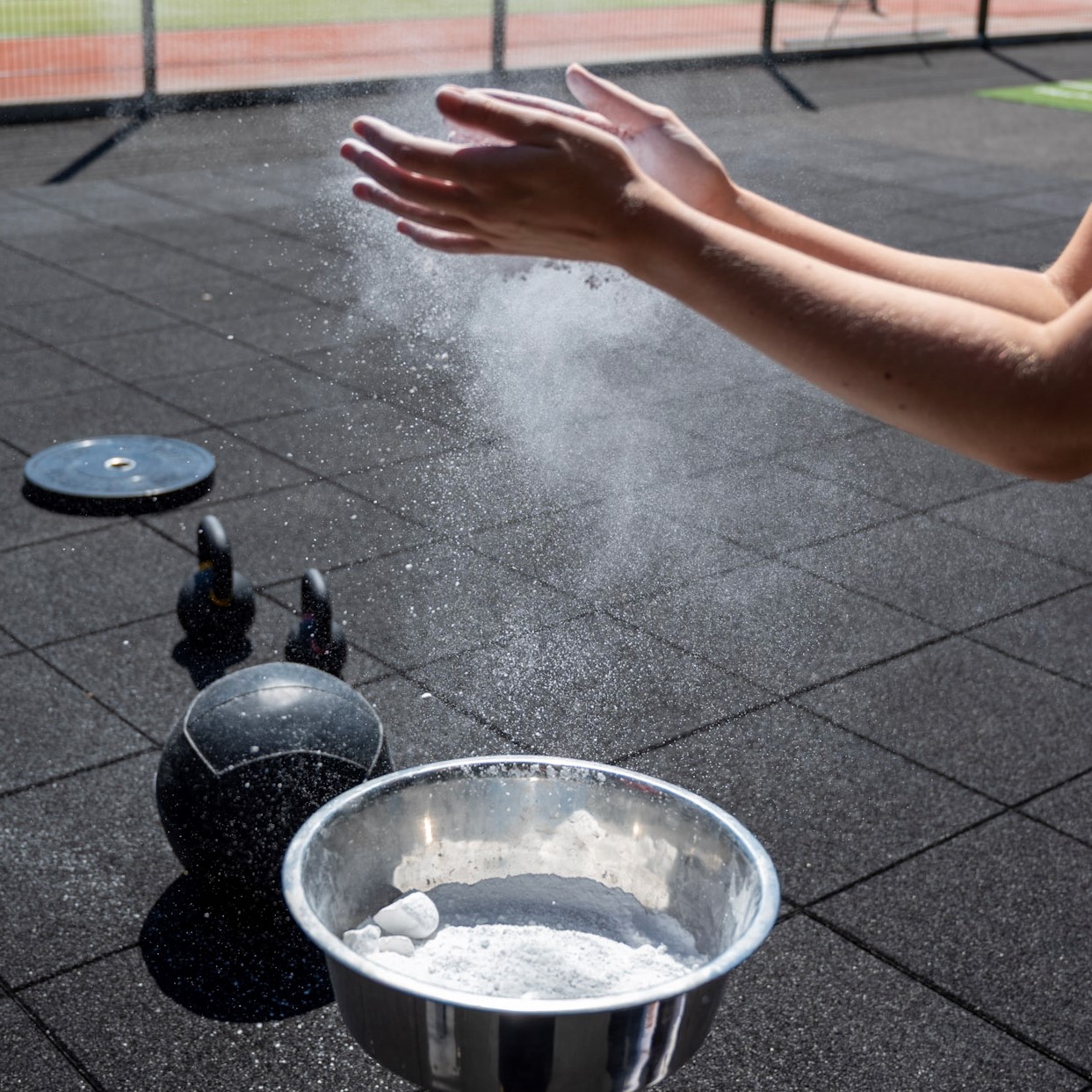 Foto von Händen mit Chalk und Kettlebells im Hintergrund