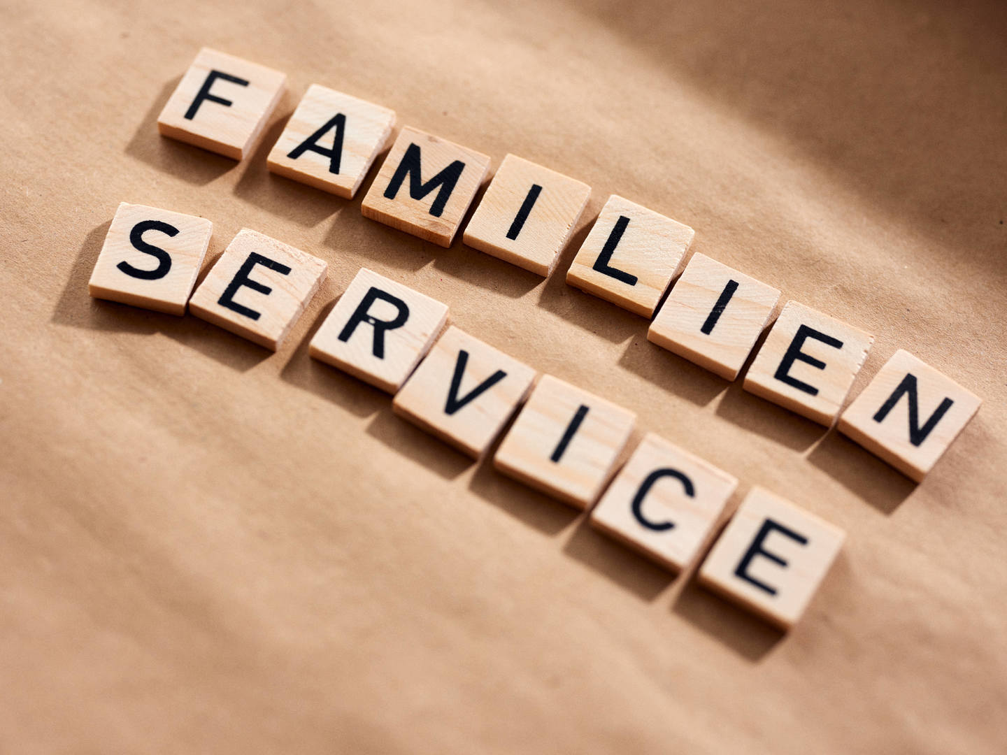 Holztäfelchen mit Buchstaben liegen auf einem Tisch und zeigen den Schriftzug "Familien Service"