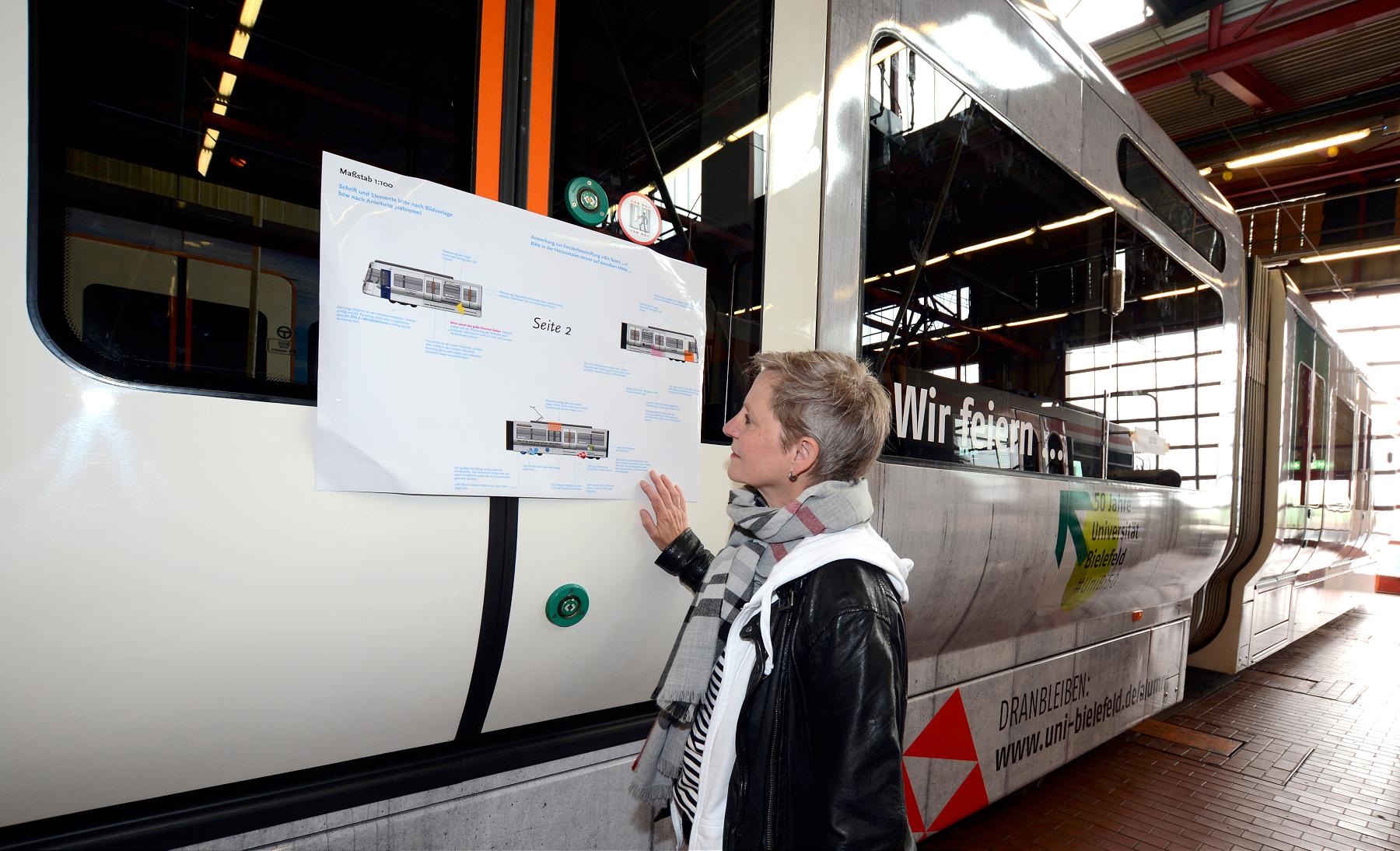 Foto von der Grafikerin Petra Breuer vor der Straßenbahn.