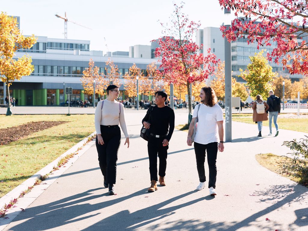 3 Promotionsstudierende gehen einen Gang entlang