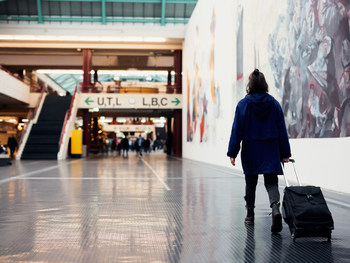 Neue Promovierende läuft mit einem Koffer durch die Halle der Universität Bielefeld