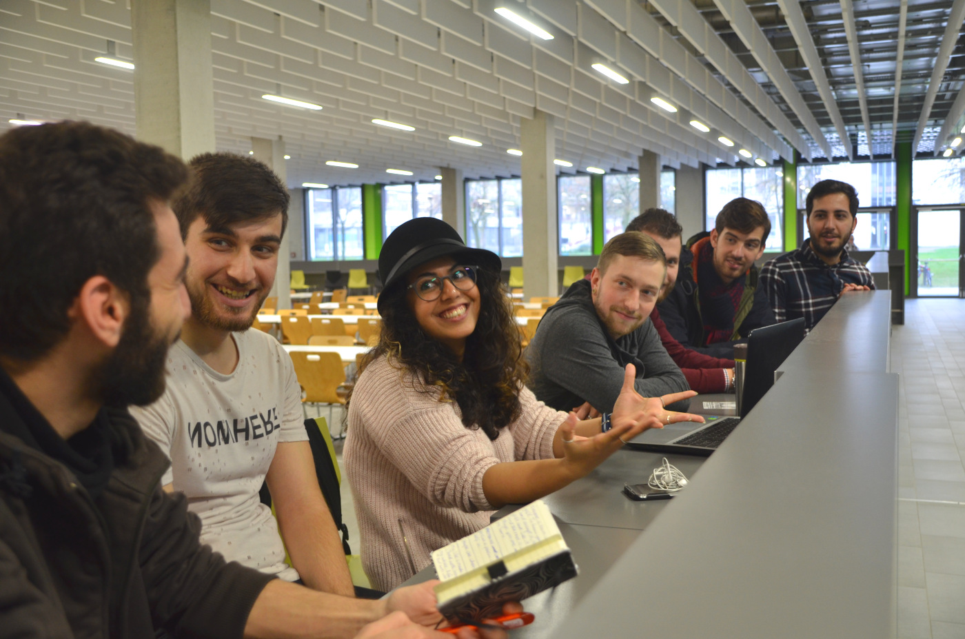 Studierende sitzen in der Mensa der Universität und unterhalten sich