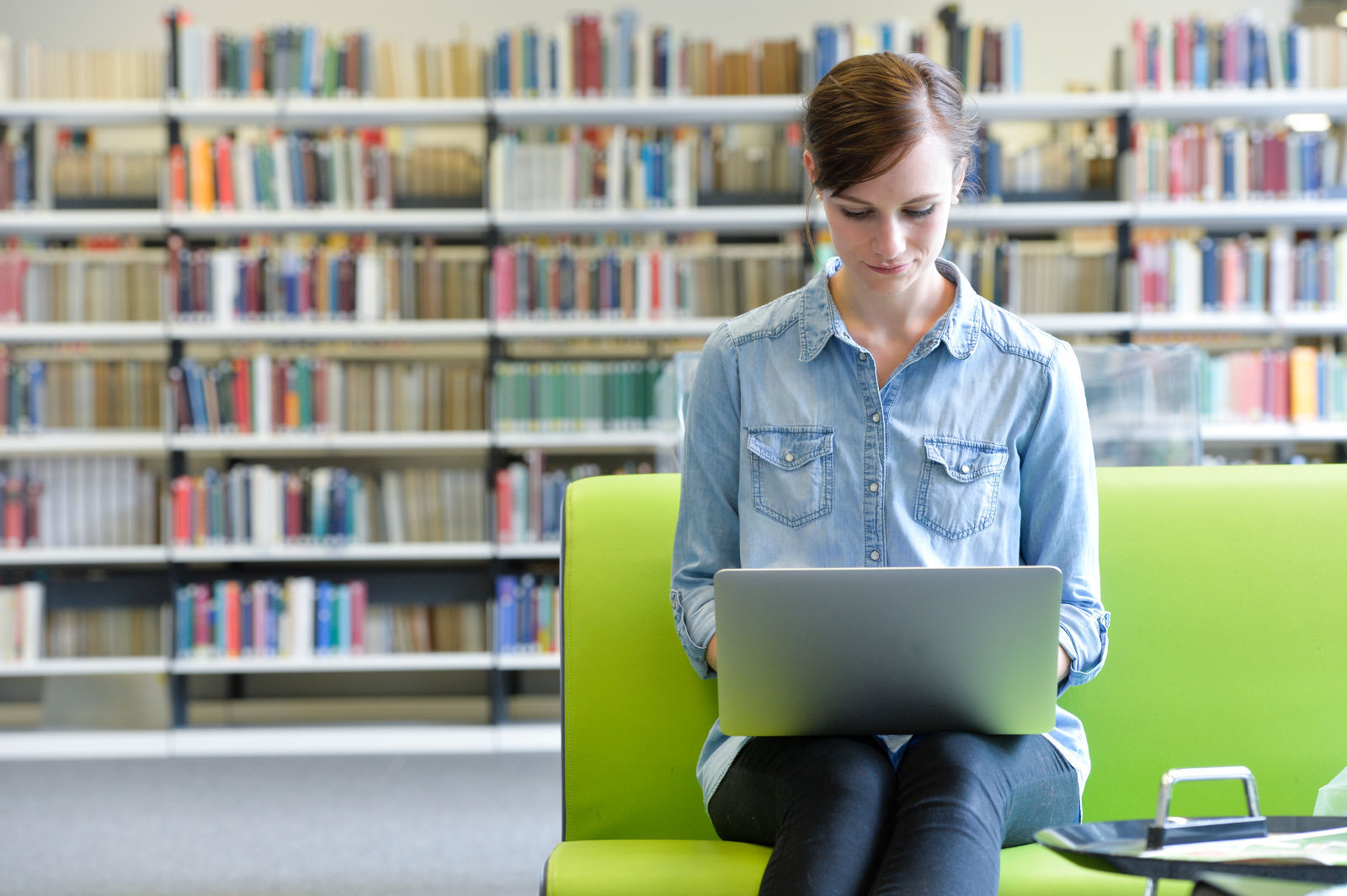 Person am Laptop in der Bibliothek